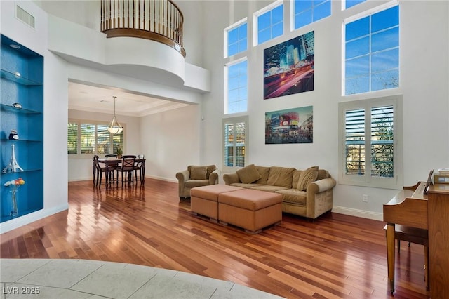 living room with a high ceiling, wood-type flooring, and ornamental molding