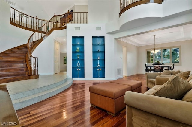 living room with a tray ceiling, hardwood / wood-style flooring, ornamental molding, and built in shelves