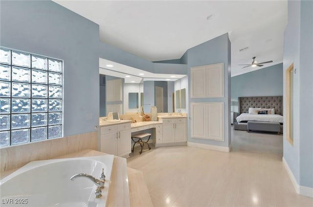 bathroom with ceiling fan, vanity, wood-type flooring, tiled bath, and vaulted ceiling