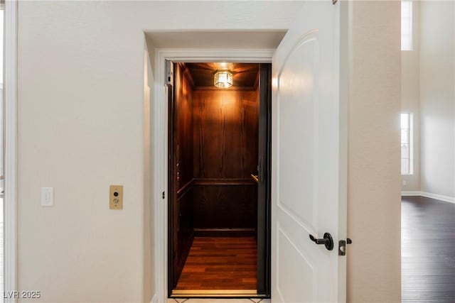 hall with hardwood / wood-style flooring and elevator