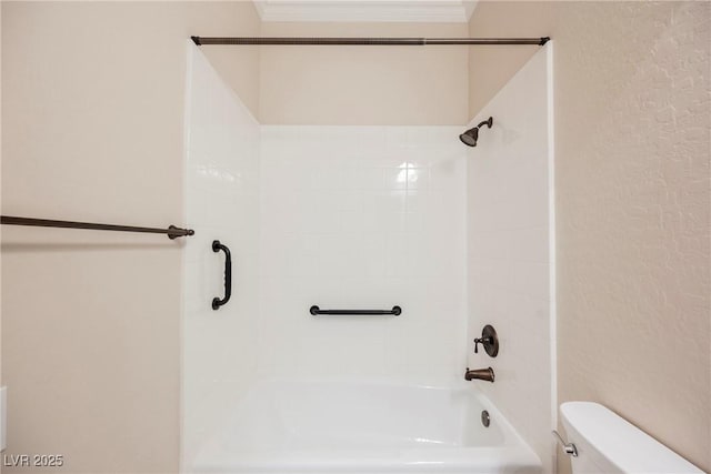 bathroom with crown molding, toilet, and tiled shower / bath combo