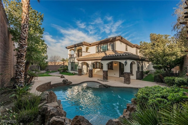 rear view of property featuring a fenced in pool, a patio area, and a balcony