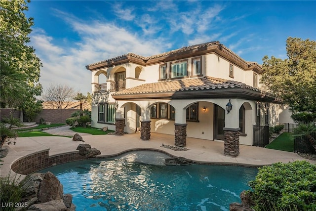 back of property with a fenced in pool, a patio area, and a balcony