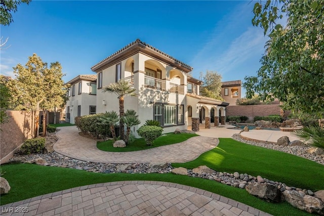 rear view of house with a patio area, a balcony, and a lawn