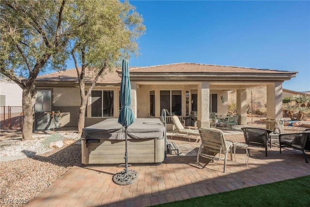 back of house with a hot tub and a patio