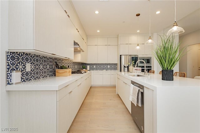 kitchen with sink, a center island with sink, hanging light fixtures, stainless steel appliances, and white cabinets