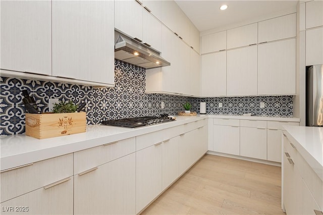 kitchen with white cabinetry, backsplash, light hardwood / wood-style flooring, and appliances with stainless steel finishes