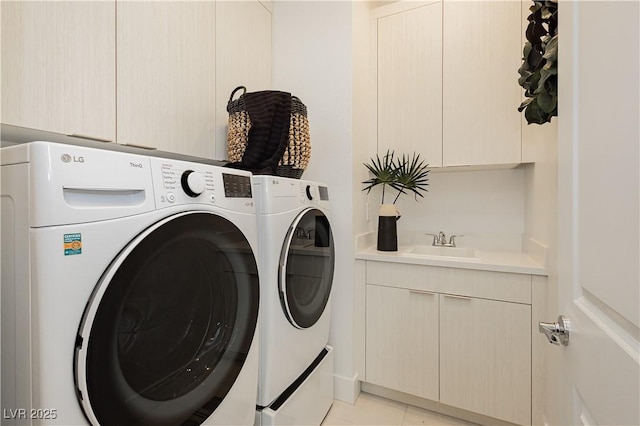 laundry area with cabinets, washing machine and clothes dryer, sink, and light tile patterned floors