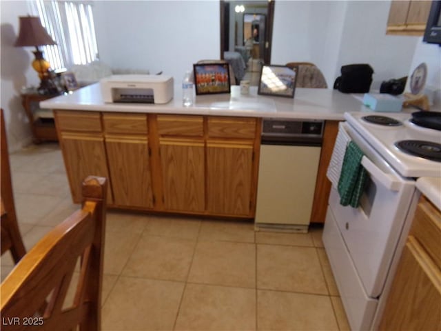 kitchen with light tile patterned floors, brown cabinets, light countertops, and white electric range oven