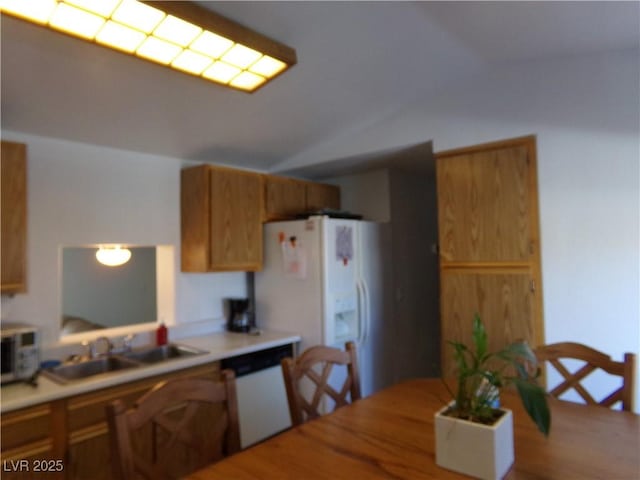 kitchen featuring brown cabinets, white appliances, light countertops, and a sink