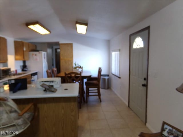 kitchen featuring kitchen peninsula, white fridge, and light tile patterned floors