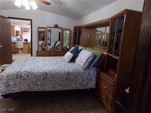 bedroom featuring lofted ceiling, tile patterned flooring, and white fridge