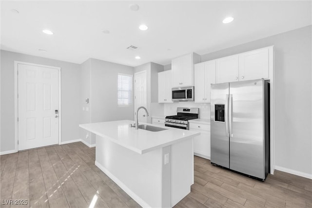 kitchen featuring white cabinetry, appliances with stainless steel finishes, sink, and an island with sink