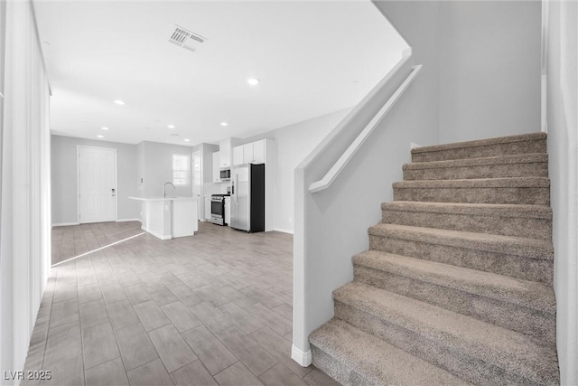 staircase with wood-type flooring and sink