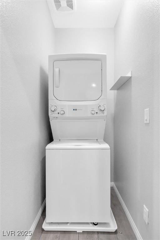 laundry area featuring stacked washer and dryer and hardwood / wood-style floors