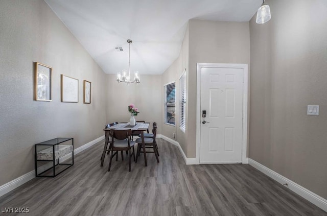 dining room with wood-type flooring, lofted ceiling, and a notable chandelier