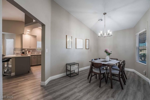 dining area featuring vaulted ceiling, dark hardwood / wood-style floors, and a chandelier