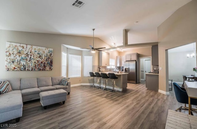 living room with hardwood / wood-style flooring, vaulted ceiling, and ceiling fan with notable chandelier