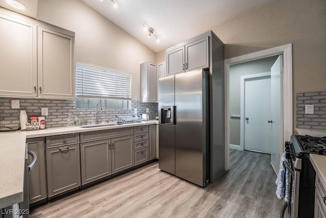 kitchen featuring sink, gray cabinets, appliances with stainless steel finishes, light hardwood / wood-style floors, and vaulted ceiling