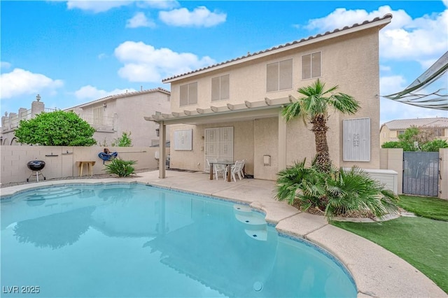 back of property with a fenced in pool and a patio area