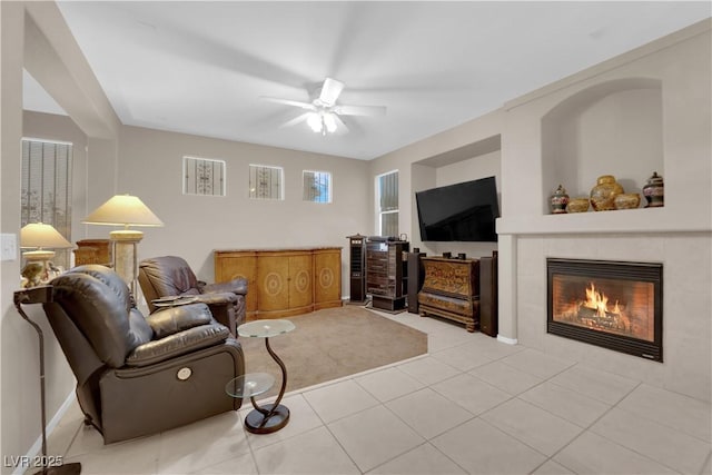 tiled living room with a tiled fireplace and ceiling fan