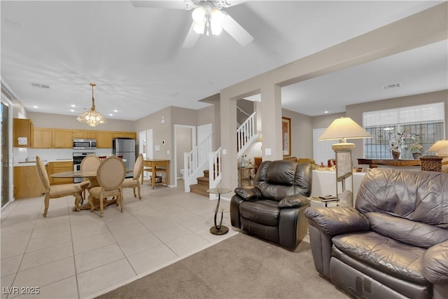 tiled living room featuring ceiling fan with notable chandelier