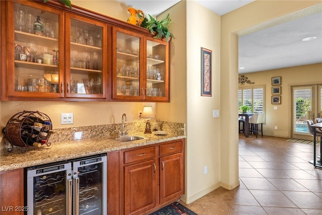 bar with wine cooler, sink, light stone counters, and light tile patterned floors