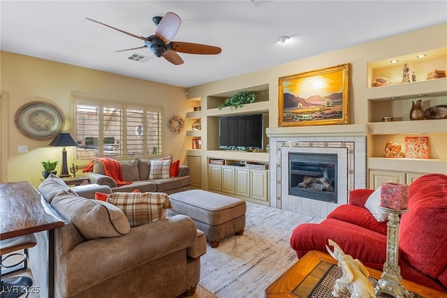 living room with ceiling fan, a fireplace, and built in features