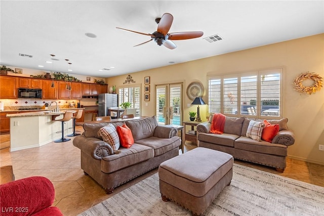 tiled living room with sink, ceiling fan, and french doors