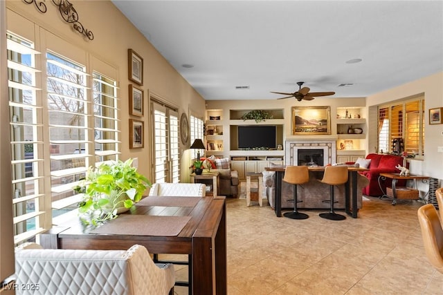 dining room featuring light tile patterned floors, built in shelves, and ceiling fan