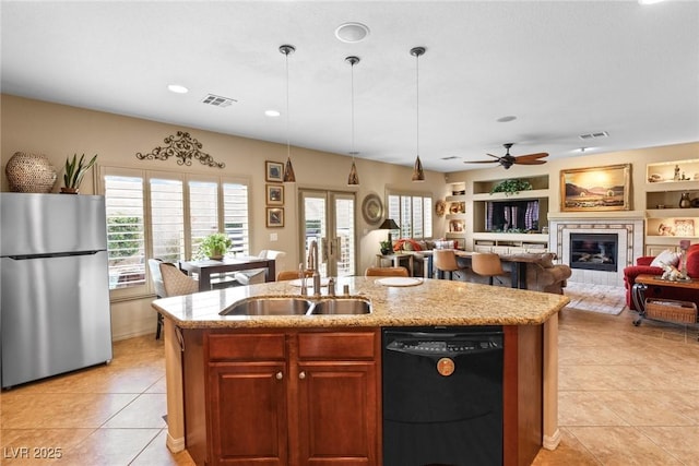 kitchen with black dishwasher, sink, stainless steel fridge, a kitchen island with sink, and built in shelves