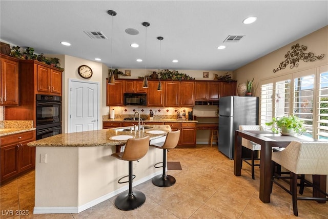 kitchen with sink, a breakfast bar area, pendant lighting, a kitchen island with sink, and black appliances