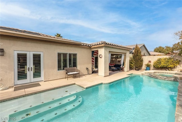 back of house with a swimming pool with hot tub, a patio, and french doors