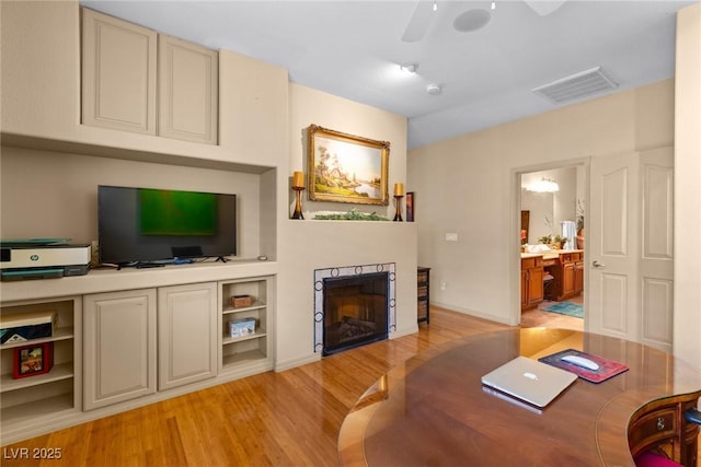 living room featuring built in shelves, ceiling fan, and light hardwood / wood-style floors