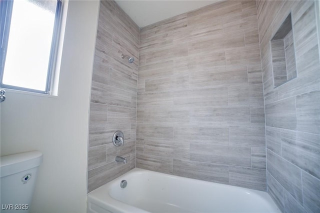 bathroom featuring toilet and tiled shower / bath