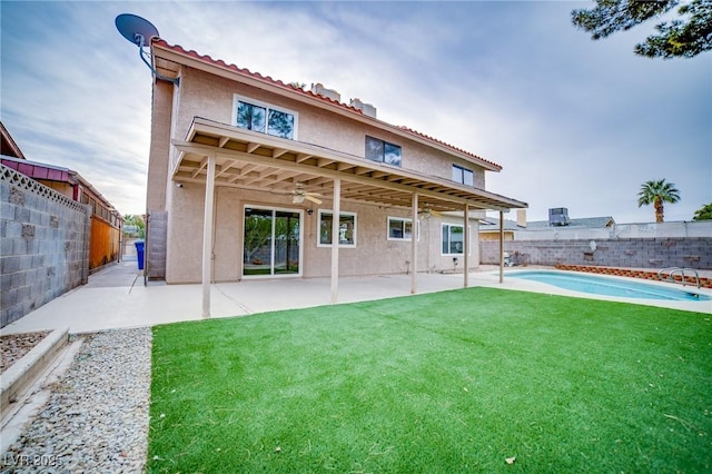 back of house with a fenced in pool, a patio, ceiling fan, and a lawn