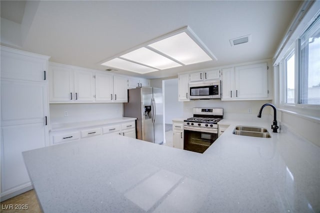 kitchen featuring sink, stainless steel appliances, kitchen peninsula, and white cabinets