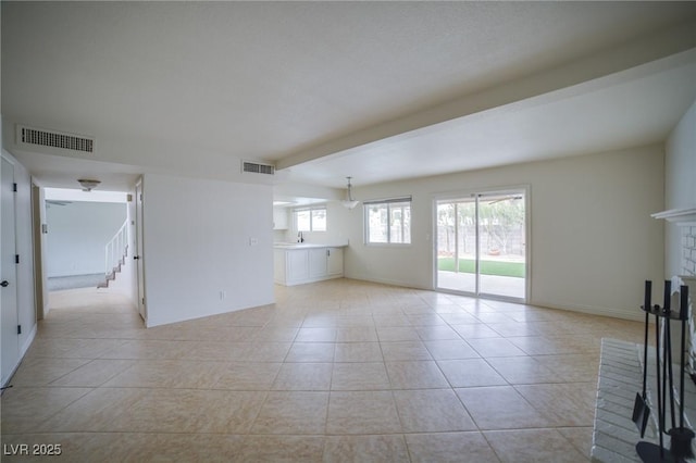 unfurnished living room with a brick fireplace, sink, and light tile patterned flooring