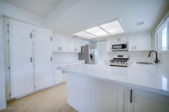 kitchen with sink, white cabinetry, light tile patterned floors, kitchen peninsula, and stainless steel appliances