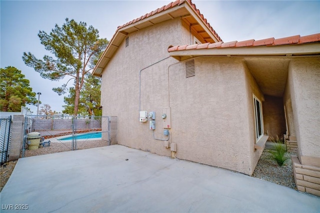 view of side of property featuring a fenced in pool and a patio area