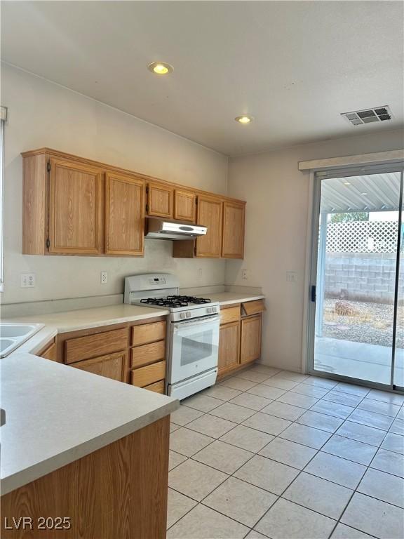 kitchen featuring white range with gas cooktop, sink, and light tile patterned floors