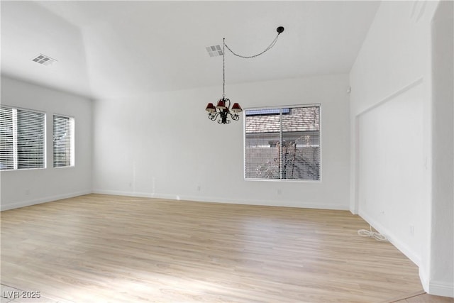 spare room with light wood-type flooring and a notable chandelier