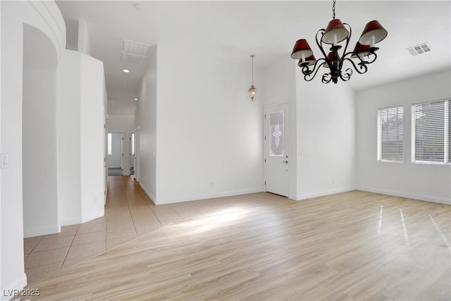 unfurnished room featuring a chandelier and light hardwood / wood-style flooring