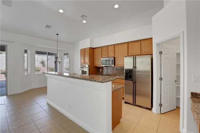 kitchen with a kitchen island, appliances with stainless steel finishes, pendant lighting, tasteful backsplash, and dark stone counters