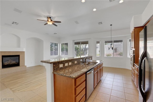 kitchen featuring sink, hanging light fixtures, light tile patterned floors, appliances with stainless steel finishes, and dark stone counters