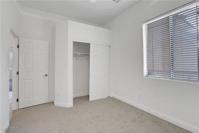 unfurnished bedroom featuring multiple windows, light colored carpet, and a closet