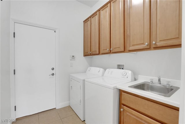 clothes washing area with light tile patterned flooring, cabinets, sink, and washer and dryer