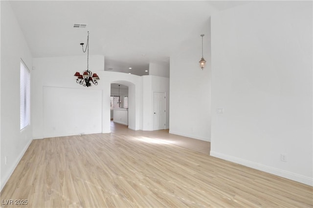 unfurnished living room with an inviting chandelier and light hardwood / wood-style flooring