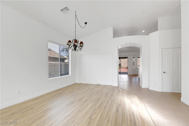 unfurnished dining area featuring lofted ceiling, a chandelier, and light hardwood / wood-style flooring