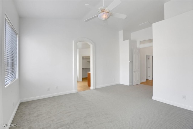 unfurnished bedroom with a spacious closet, vaulted ceiling, light colored carpet, and ceiling fan